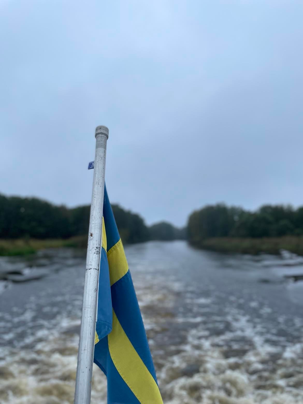 Aktern på en båt med svallande vågor bakom. Vänster i bild syns svenska flaggan. 